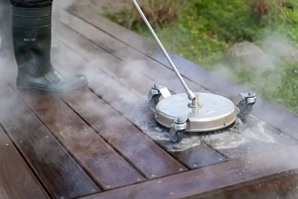 Højtryksrenser med hedevand som fjerner algevækster på en træterrasse