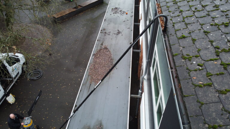 Professionel rensning af tagrender på etageejendom udført fra jorden med specialudstyr