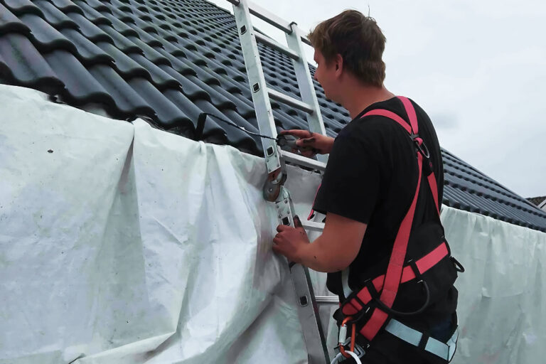 Tagmaler udfører tagrmaling med stige og sikkerhedsudstyr.