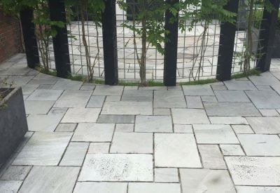 Opfrisket terrasse mellem træstammer i Middelfart efter fliserens