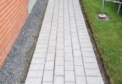 Samme flisegang i Middelfart efter fliserens, ren og lys mod græsplænen